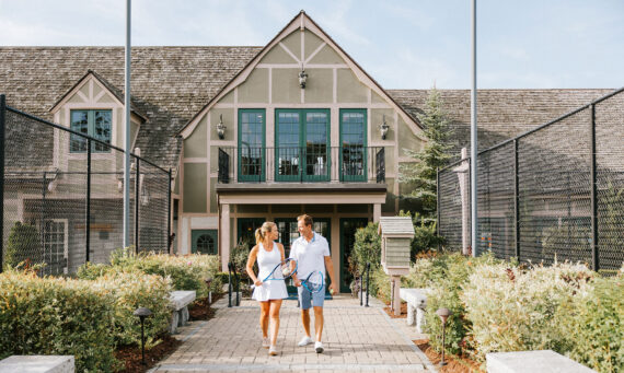 A couple strolls infront of the exterior of the Bar Harbor Club.