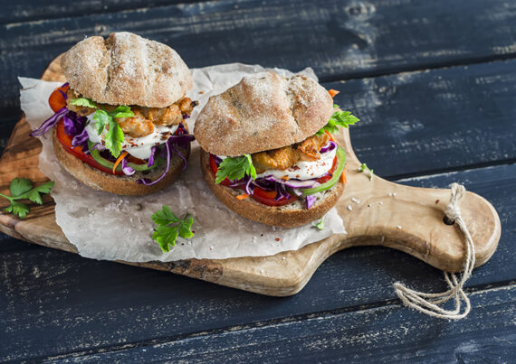 Homemade crispy fish burger on a dark rustic wooden board