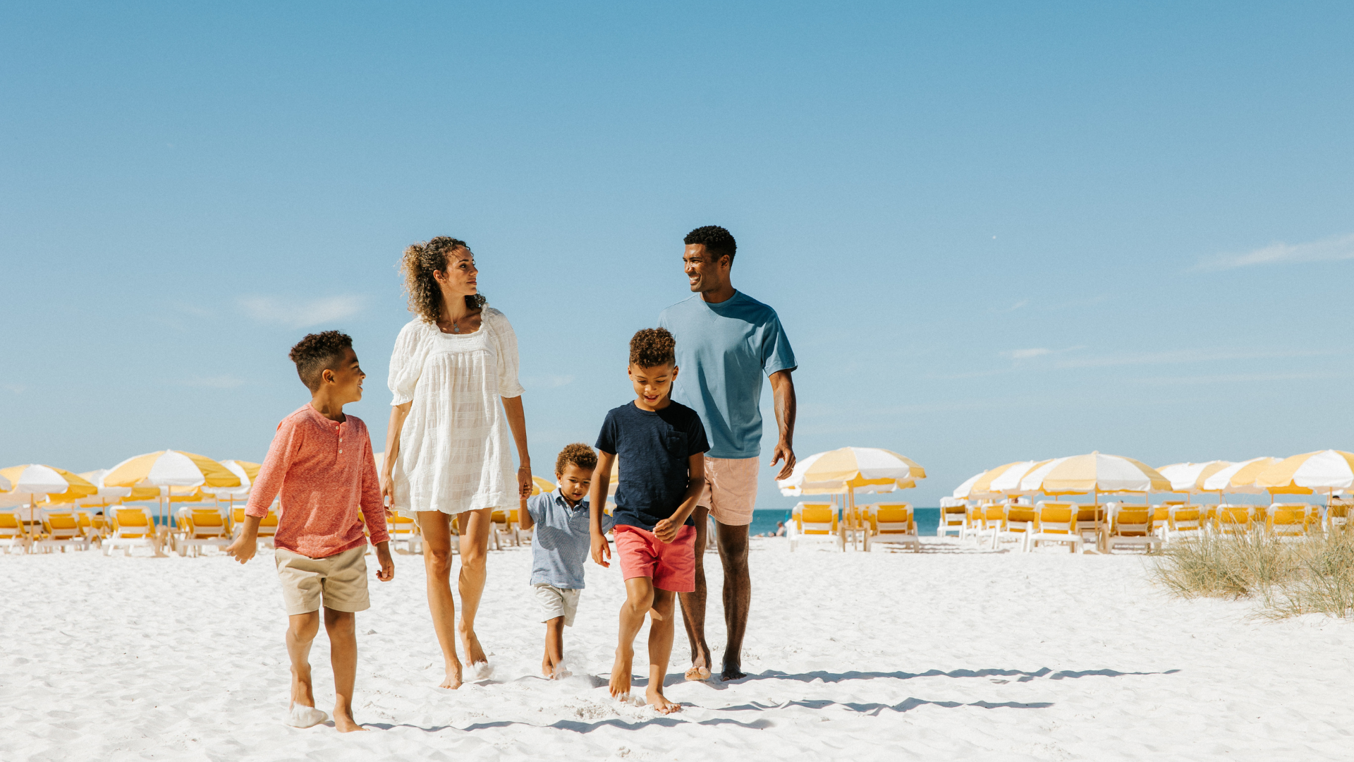 A family strolls along the white powder sand of Clearwater Beach in Florida.
