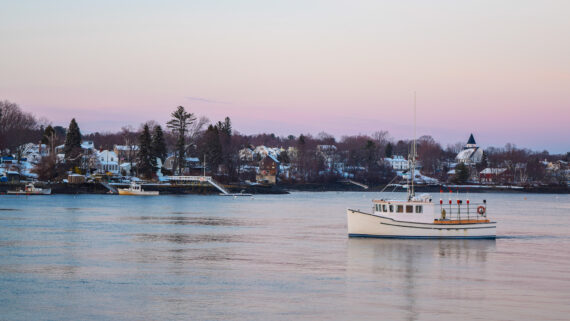 A small lobster boat cruises the waters of the Piscataqua River in Portsmouth, New Hampshire.