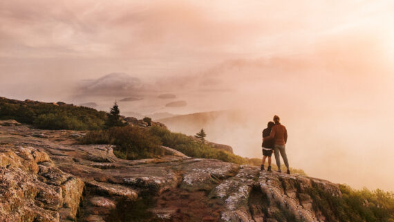 Mother and son stand at the summit of Cadillac Mountain at sunrise in Bar Harbor, Maine.
