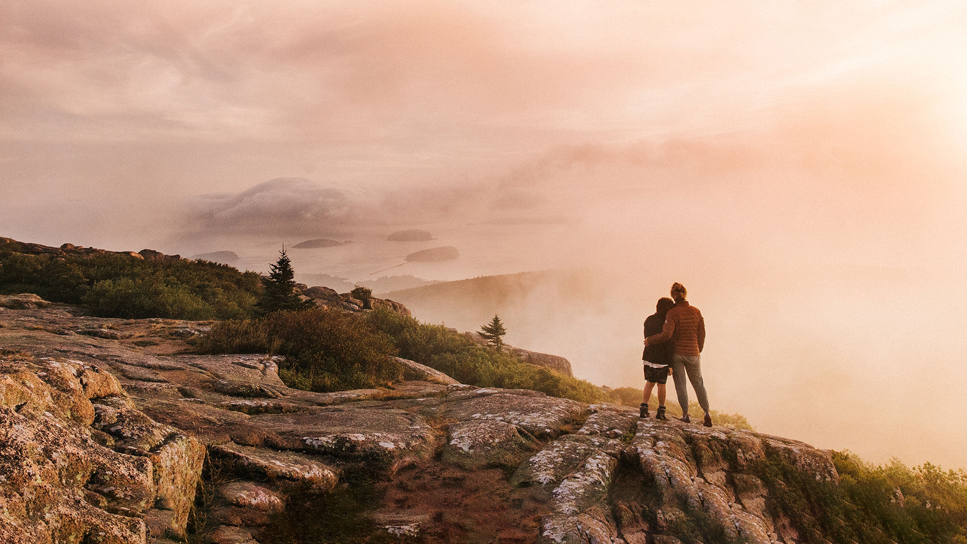 Mother and son stand at the summit of Cadillac Mountain at sunrise in Bar Harbor, Maine.