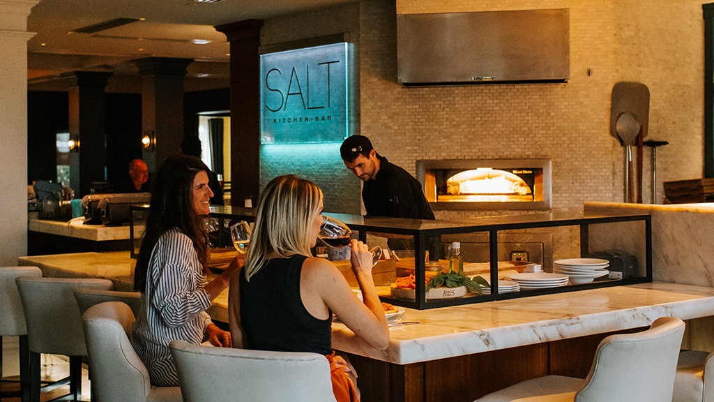 A chef prepares dishes before diners at the Chef's Bar in Salt Kitchen & Bar.