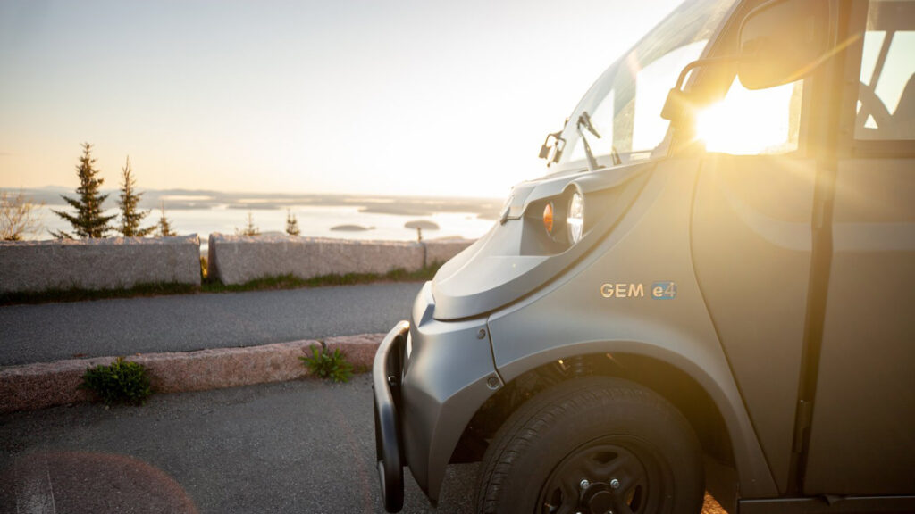 Acadia GEM electric vehicle parked on the road at sunset overlooking the water.
