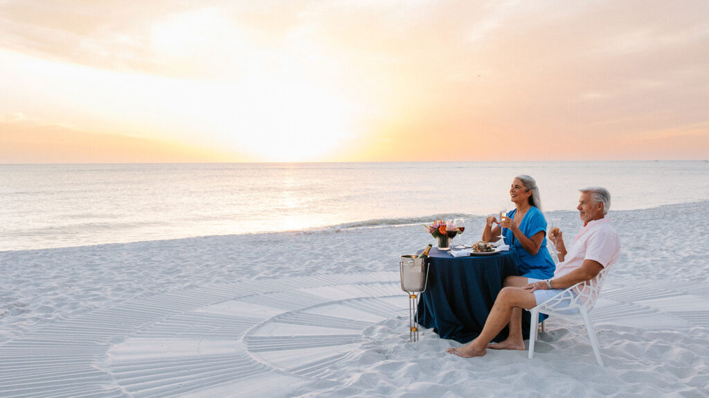 A couple dines on the sand at Sunset at Edgewater Beach Hotel.