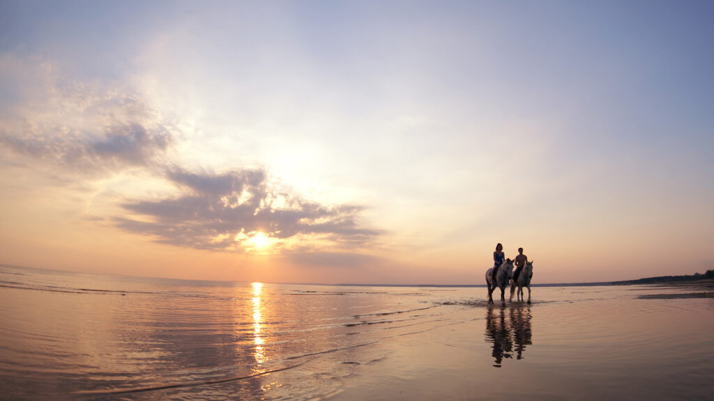 A couple rides horses on Jensen Beach in Hutchinson Island, Florida.