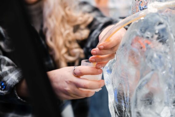 A woman serves herself a shot through the ice luge.