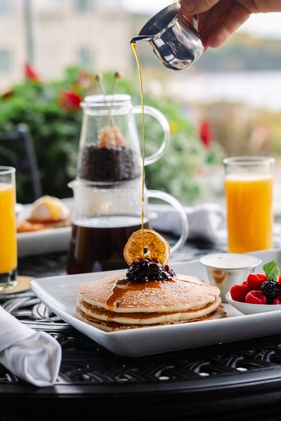pancakes served with warm syrup and berries