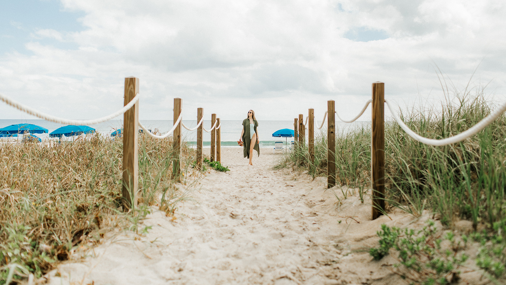 A woman strolls an entrance point to the beach in Delray Beach.