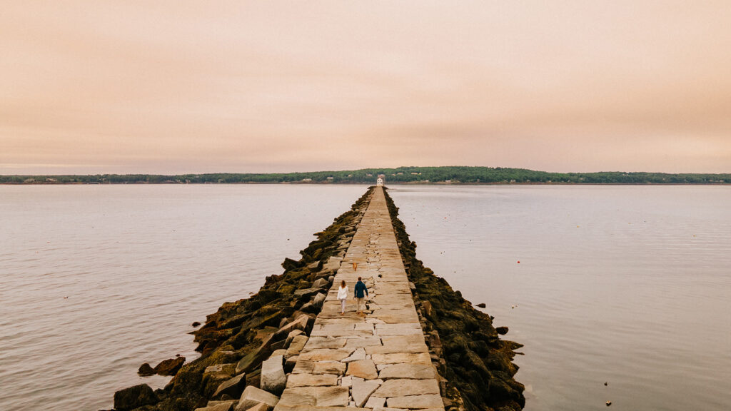 A couple strolls along the Rockland Breakwater in Rockport, Maine.