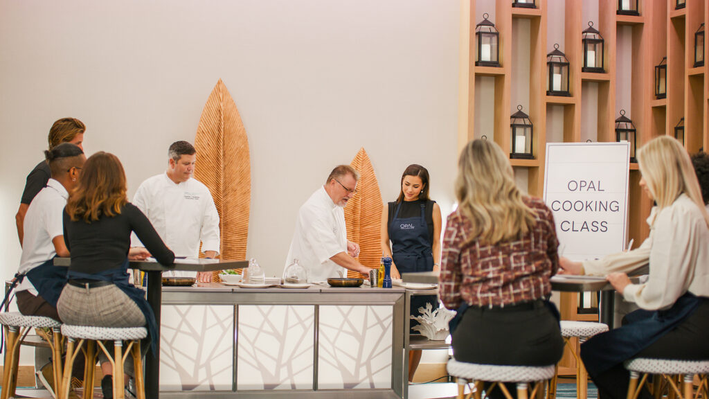 A group of people participate in a cooking class led by Opal chefs.