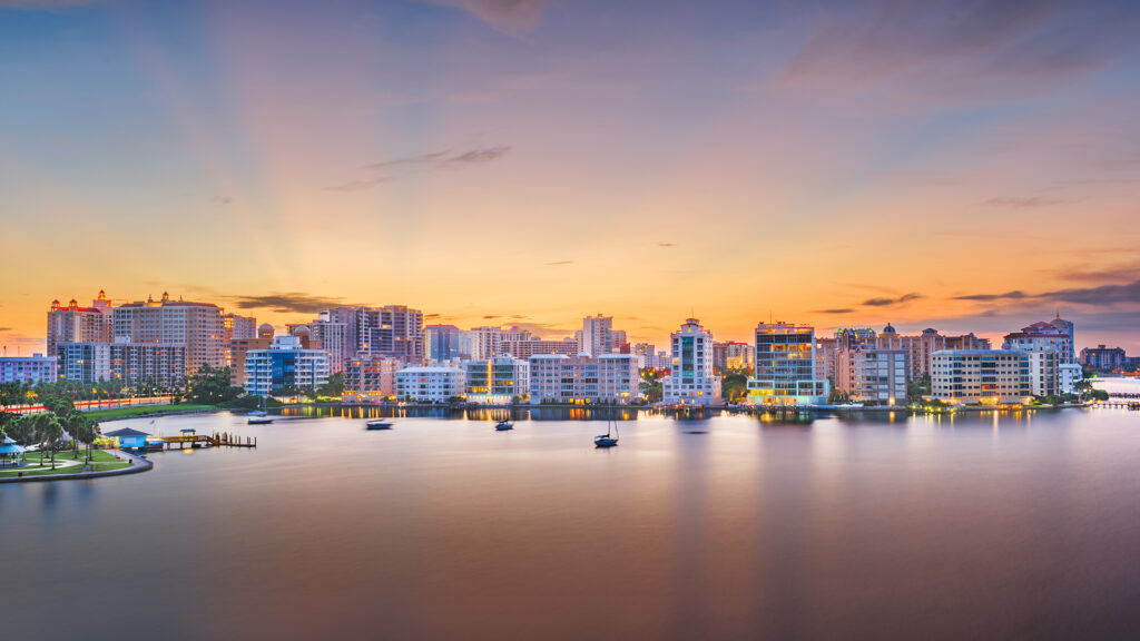 A scenic view of a sunset city skyline of Sarasota over water.