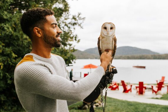 An owl perches on a mans arm at Lake Placid Lodge.