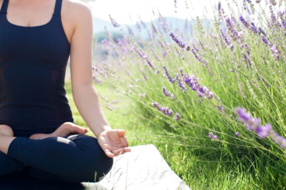 A woman does yoga in a garden.