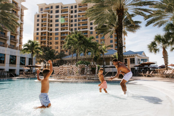 view of hotel with pool and family playing in the pool