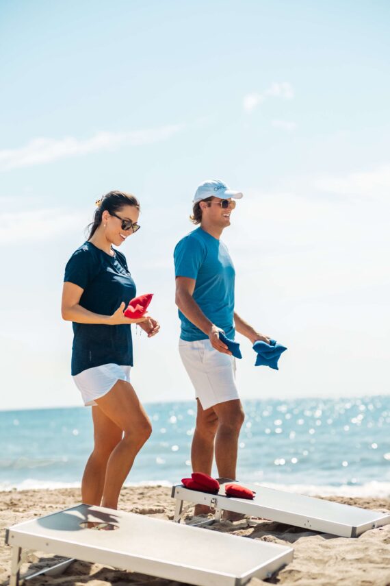 Team members play cornhole on the beach.