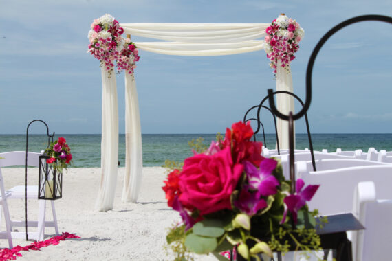 Chairs and altar with pink flowers on the beach facing the ocean