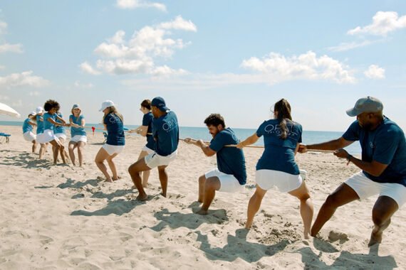 A group plays tug-of-war on the beach.