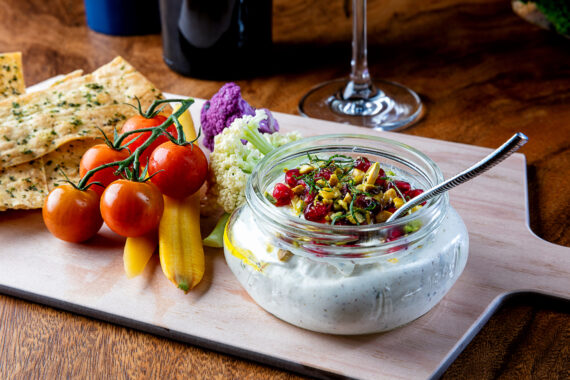 fresh vegetables and crackers on a board served with a dip