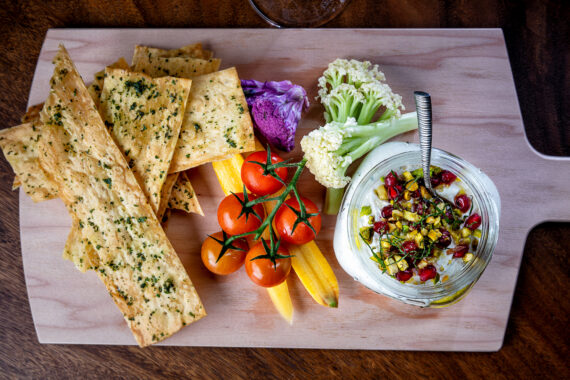 fresh vegetables and crackers on a board served with a dip