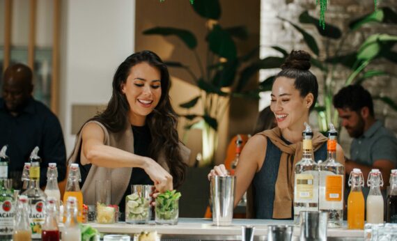 Two women make cocktails in a teambuilding activity.