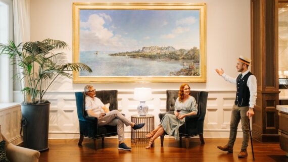 a couple drinking wine in front of a painting of the belleview inn
