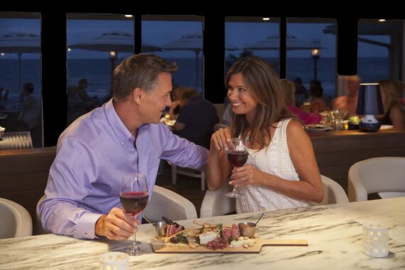 couple drinking wine and eating a cheese board at the bar