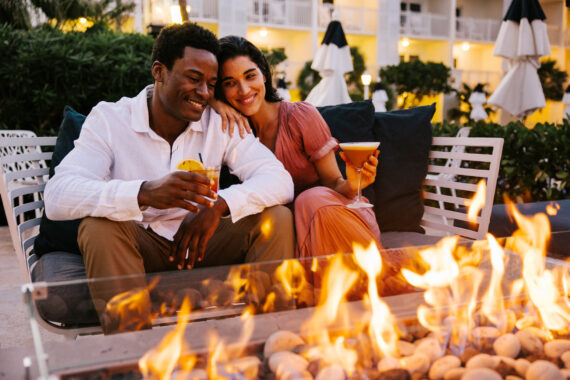 a couple enjoying cocktails by a fire pit