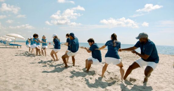Two teams compete in tug-of-war on the beach.