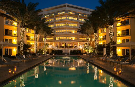 the pool at night with the palm trees lit up with string lights