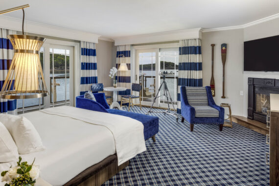 Luxury hotel suite at Harborside in Bar Harbor decorated in blue tones with a large bed overlooking a balcony.