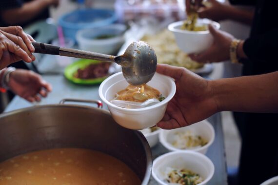 A volunteer ladles food into a bowl.