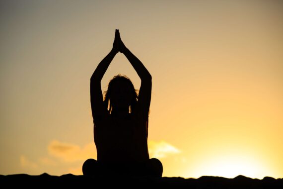 A person does a yoga pose at sunset.